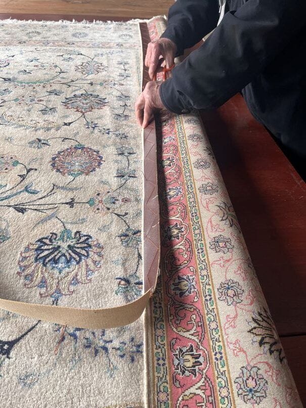 Entfernen der alten verschlissenen Stoffbänder bei einem Tabriz Seidenteppich – Vorbereitung für die Restaurierung in Aachen
Bild 2 (mitte – Hand bei der Ar