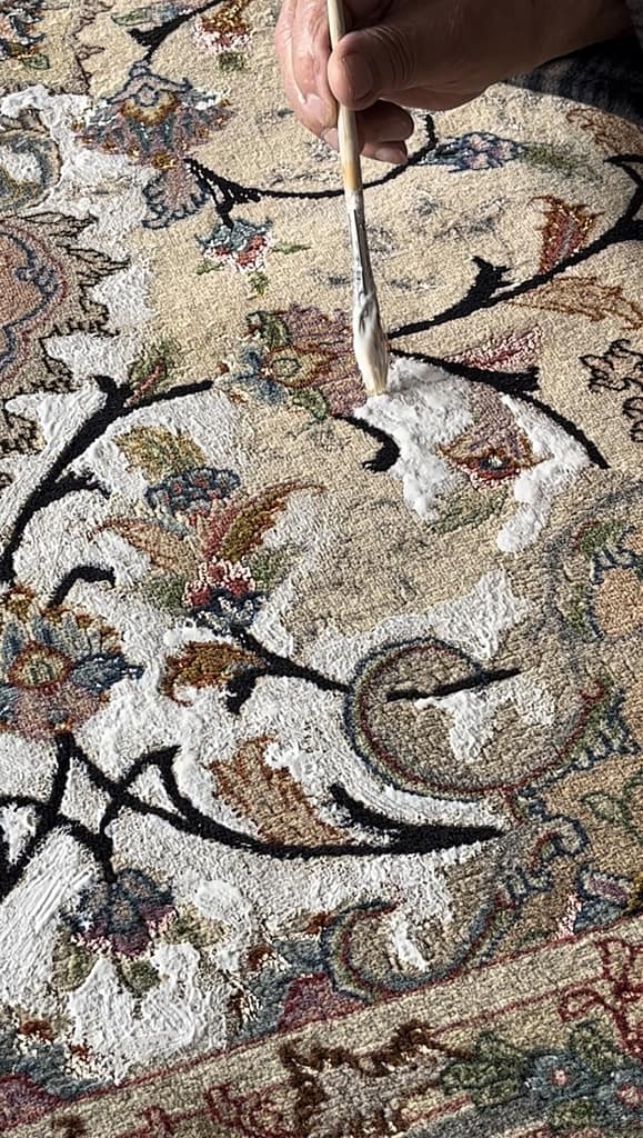 Persischer Täbriz während der Farbrestaurierung – Entfärbungsmittel wird auf Wasserschaden-Bereiche aufgetragen